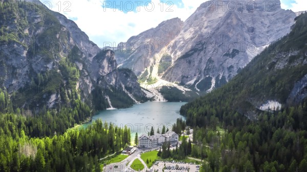 Stunning aerial view of lake braies with the iconic seekofel mountain and a charming hotel nestled amidst the lush greenery of the italian dolomites in summer