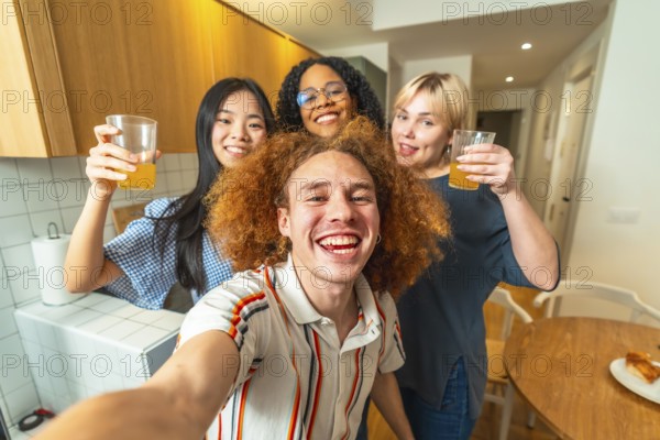 Group of cheerful multi ethnic friends taking a selfie while drinking juice, celebrating and having fun together in a modern kitchen