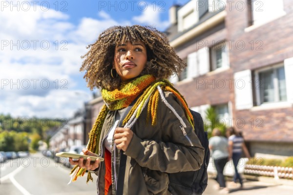 Distracted young latin woman with warm clothes using phone in the city