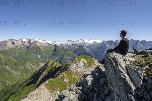Mountaineer sitting on a rock in front of a mountain panorama with Großvenediger, mountain landscape with mountain peaks of the Venediger group, view from the summit of the Gösleswand, Lasörling group, Hohe Tauern National Park, East Tyrol, Tyrol, Austria, Europe