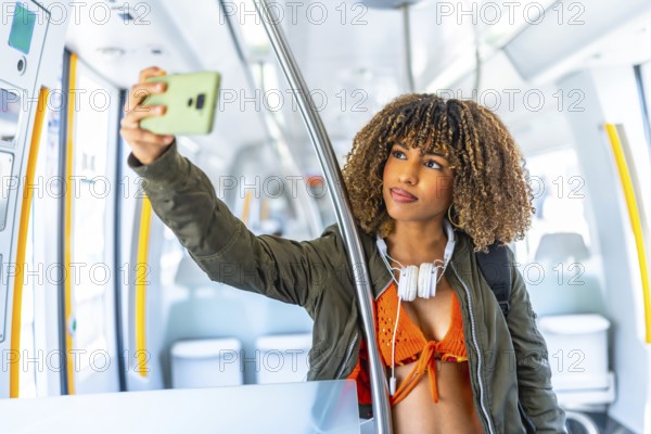 Latin young beauty woman with casual clothes and curly hair taking selfie standing on the train
