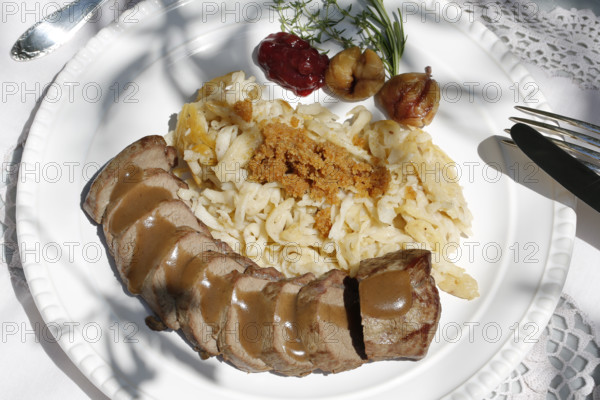 Swabian cuisine, roast venison with spaetzle, chestnuts and breadcrumbs, breadcrumbs, saddle of venison arranged on a plate, gravy, game dish, meat, main course, gravy, cutlery, knife, fork, grandmother's kitchen, regional, home cooking, typical Swabian, traditional cuisine, festive tablecloth, food photography, studio, Germany, Europe