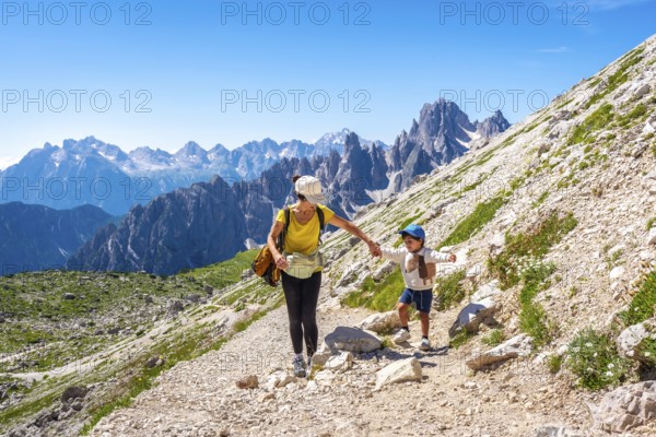 Tourists enjoying a summer hike on a mountain trail in the italian dolomites, with the tre cime di lavaredo peaks in the background