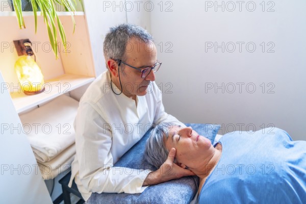 Mature male therapist doing an oriental neck massage to a mature woman in a clinic