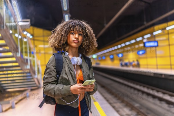 Beauty woman with curly hair and brunette skin using phone while waiting the underground metro