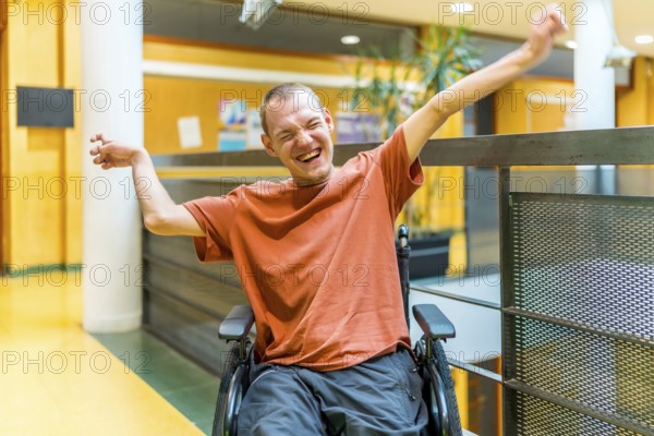 Successful man with disability celebrating in a modern coworking sitting on wheelchair and raising arms while smiling alone