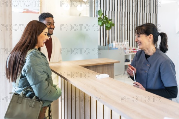 Happy couple engaging with a friendly receptionist in a bright, modern dental clinic, enjoying a positive healthcare experience