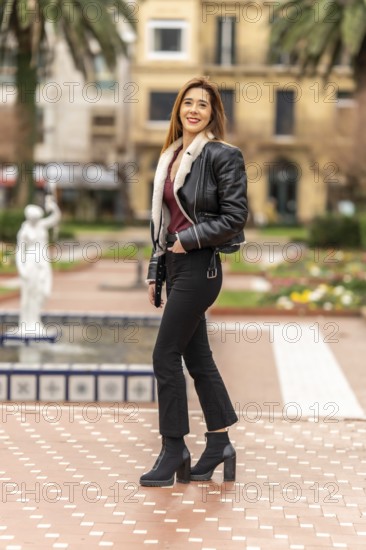 Fashionable woman standing in urban park, showcasing her trendy outfit and enjoying the pleasant weather