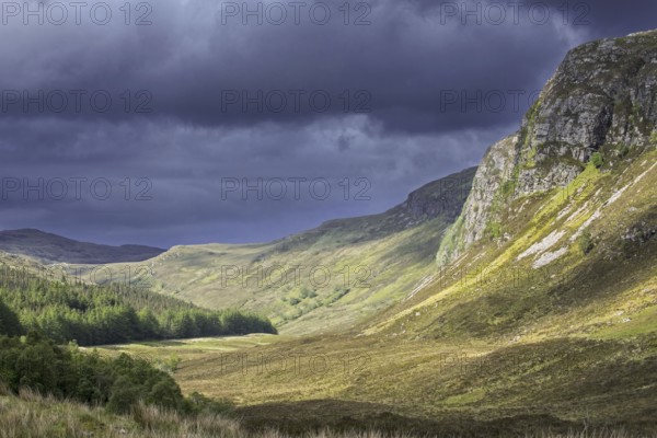 Mountain scenery showing dark rain clouds rolling in over sunny hillside and valley in Wester Ross, Scottish Highlands, Scotland, UK