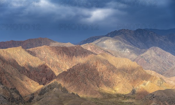 Red and orange mountains in atmospheric light, dramatic cloudy sky, mountain landscape near Kazarman, Naryn region, Kyrgyzstan, Asia