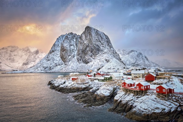 Famous tourist attraction Hamnoy fishing village on Lofoten Islands, Norway with red rorbu houses. With falling snow in winter on sunrise