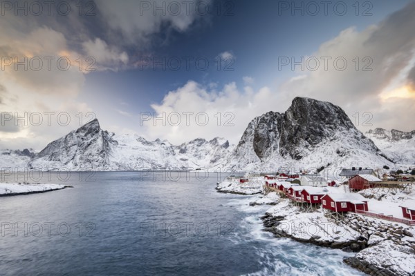 Rorbuer cabins of Hamnoy by the fjord, snowy mountains in the back, Hamnøy, Reine, Moskenesøya, Lofoten, Norway, Europe