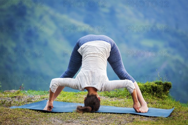 Yoga exercise outdoors, woman doing Ashtanga Vinyasa Yoga asana Prasarita padottanasana D, wide legged forward bend pose outdoors