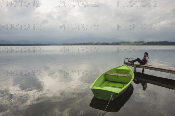 Woman 50-55, wooden jetty, green rowing boat, Hopfensee, Hopfen am See, near Füssen, Ostallgäu, Allgäu, Bavaria, Germany, Europe