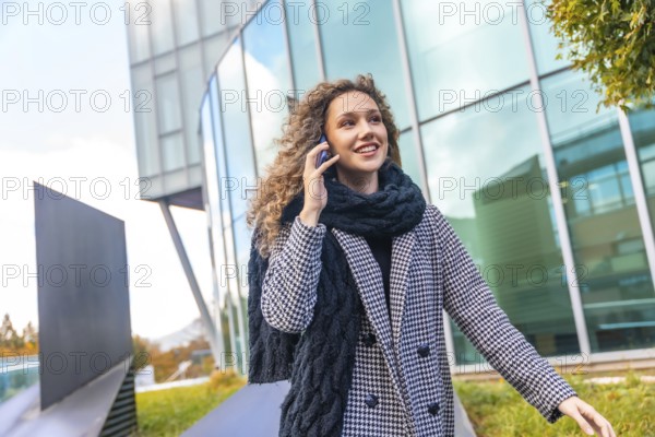 Portrait of a cute woman in elegant warm clothes using phone in the city