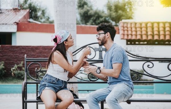 Young couple arguing sitting on a park bench, Concept of aggressive couples in the park. Upset couple arguing on a park bench. Man arguing with his girlfriend sitting in a park