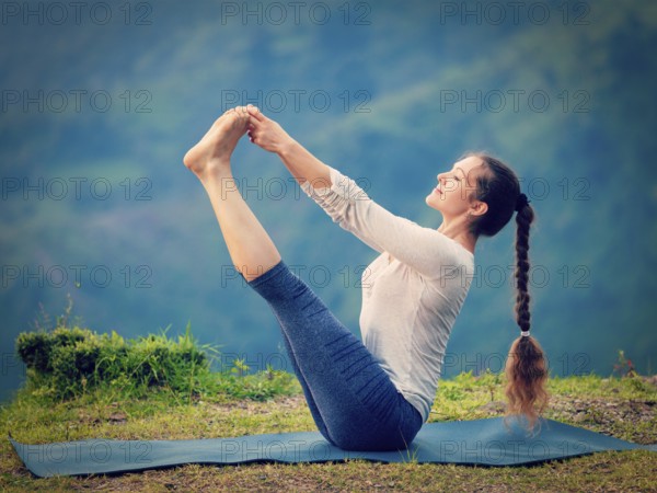 Yoga exercise outdoors, woman doing Ashtanga Vinyasa Yoga balance asana Ubhaya padangusthasana Big Double Toe Yoga Pose in Himalayas in India. Vintage retro effect filtered hipster style image