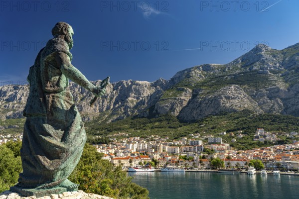 Statue of St Peter in front of the city view of Makarska and the Biokovo Mountains, Croatia, Europe