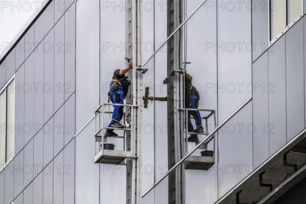 Window cleaner, facade cleaning, window cleaning, on a glass facade in Düsseldorf, ladder cage from the roof