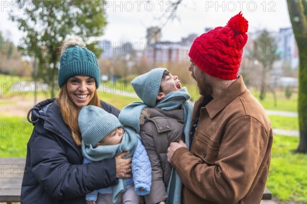 Happy family enjoying a winter day together in a park, wearing warm clothes and woolen hats