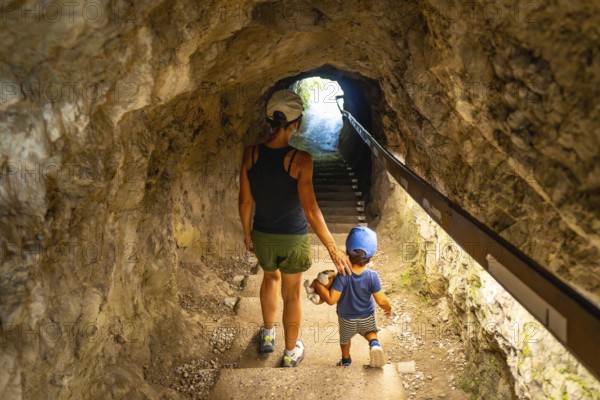 Mother and son walking up the stairs in a tunnel carved into the rock face at tolmin gorge in slovenia