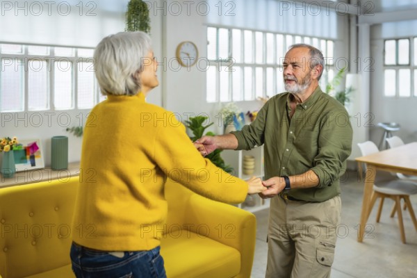 Happy hispanic senior couple dancing salsa in the living room