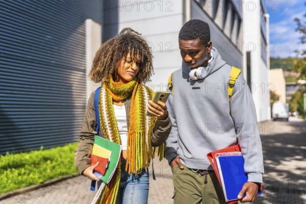 Multi-ethnic students checking information with the mobile phone walking along the university campus