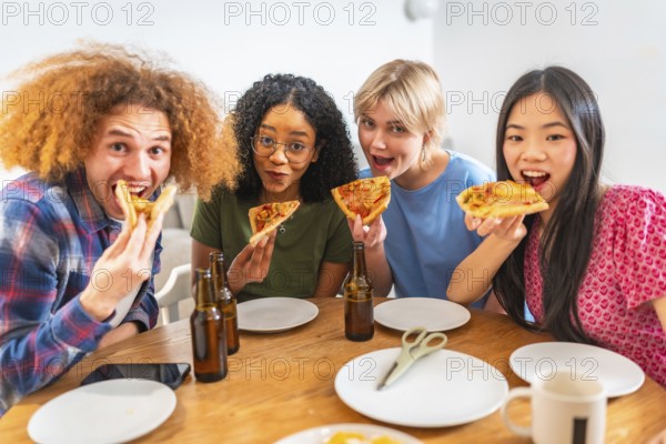 Group of young diverse friends eating pizza slices and drinking beer, having fun together at home