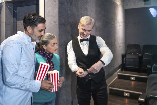 Couple entering a movie theater, holding popcorn buckets while the usher checks their tickets, enjoying a casual and happy evening together