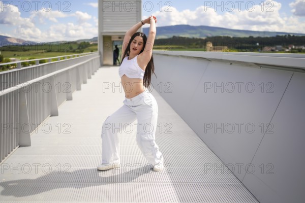 Full length portrait of a sensual caucasian woman dancing urban dance on a bridge