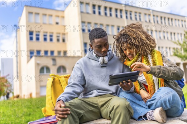 Group of diverse students looking at digital tablet sitting outdoors