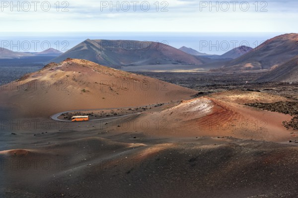 Orange-coloured coach with tourists drives through the fire mountains of Timanfaya National Park, round trip, Montanas del Fuego, Lanzarote, Canary Islands, Spain, Europe