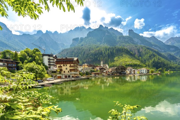 Stunning summer view of alleghe village reflecting on the emerald waters of lake alleghe, surrounded by the majestic dolomites