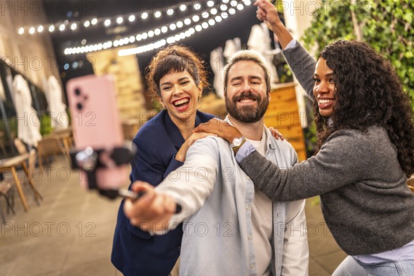 Happy hipster man recording online video blog with two female diverse friends at night party
