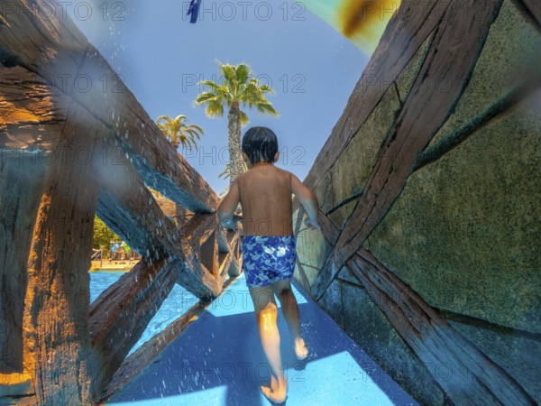 Child running through a water park during summer vacation in alicante, spain, enjoying the refreshing spray and the thrill of the water