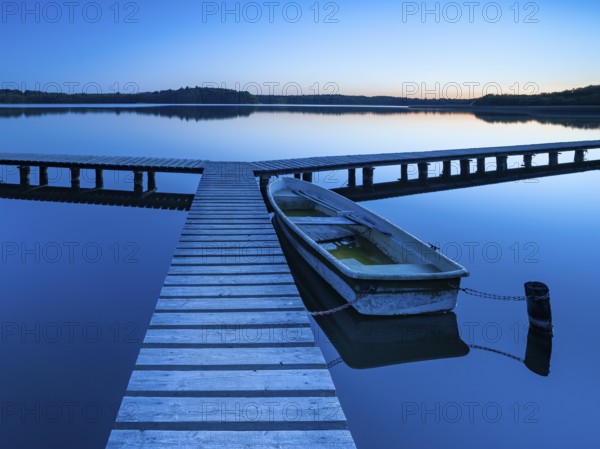 Wooden jetty with rowing boat at dusk, after sunset on Lake Schaalsee, Mecklenburg-Western Pomerania, Germany, Europe