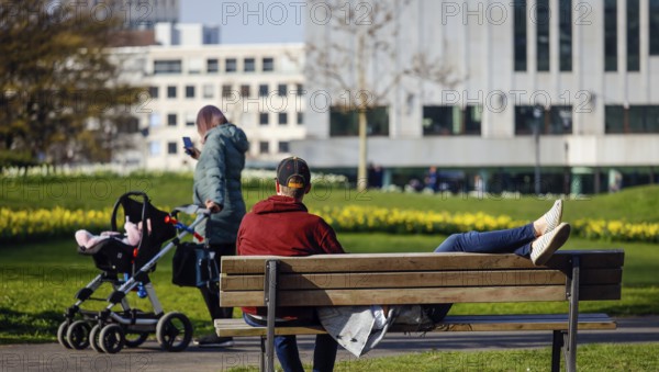 A couple relaxing on a park bench in the city garden in times of the corona crisis, Essen, Ruhr area, North Rhine-Westphalia, Germany, Europe