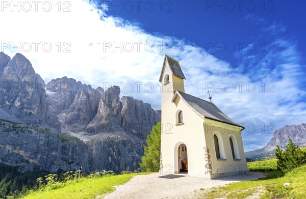 Scenic view of a charming church nestled in the italian dolomites, with the breathtaking peaks creating a stunning backdrop under a vibrant blue sky