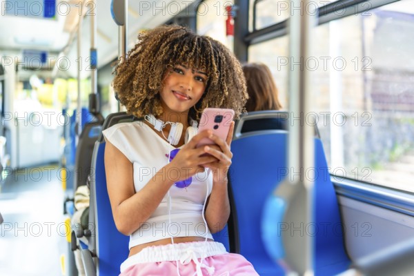 Latin young beauty woman smiling at camera while using phone sitting on urban bus