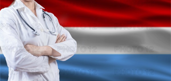 Doctor with crossed arms on Luxembourg flag. Luxembourg health and care concept. Female doctor on Luxembourg flag