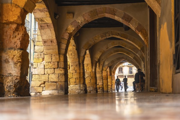 Tourists walking through the arches of the medieval city of tarragona, spain, enjoying the historical architecture
