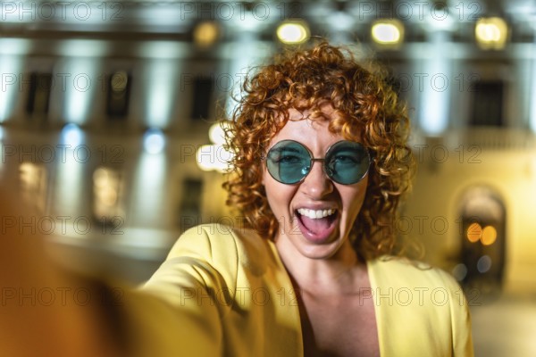 Happy woman laughing while taking selfie at city at night