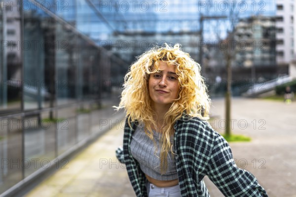 Caucasian woman with curly blonde hair joyfully dancing to modern urban music in the vibrant city, exuding carefree energy and happiness
