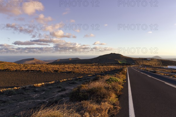 Road leads through hilly volcanic landscape, Famara Mountains, evening sky, Cumulus, Los Valles, Lanzarote, Spain, Europe