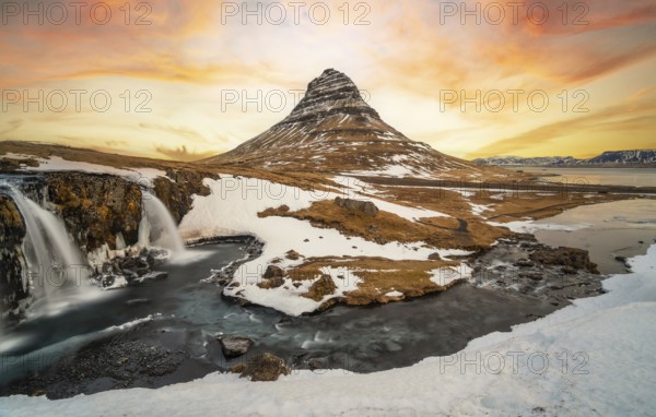 Beautiful sunrise on the famous Kirkjufell mountain next to the waterfall in winter in Iceland