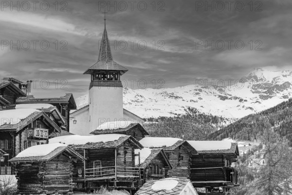 Old wooden houses with snow-covered roofs and the Saint Theodule church in the historic village centre, black and white photograph, Grimentz, Val d'Anniviers, Valais Alps, Canton Valais, Switzerland, Europe