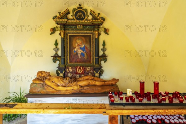 Reclining wooden statue of jesus christ and painting of madonna with child inside the santa maddalena church in val di funes, dolomites, italy