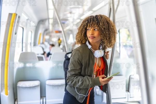 Cool latin woman using phone while looking distracted standing on the train