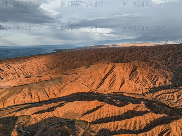 Landscape of eroded hills, badlands at sunset, Issyk Kul Lake in the background, aerial view, Canyon of the Forgotten Rivers, Issyk Kul, Kyrgyzstan, Asia