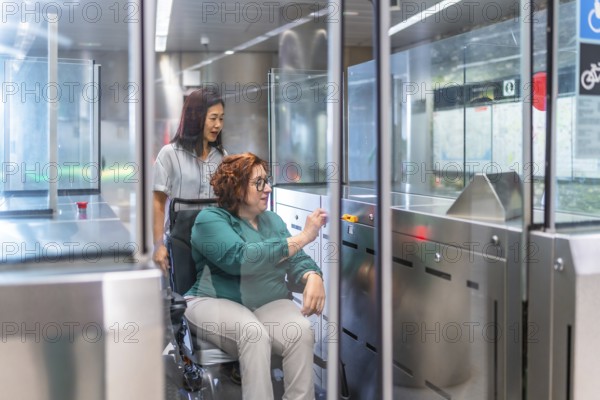 Disabled woman and chinese caregiver at the entrance of the metro introducing the ticket at the automatic doors